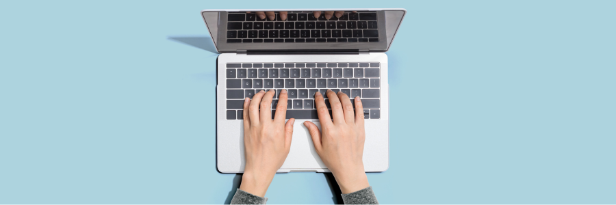 Hands typing on laptop with blue background.